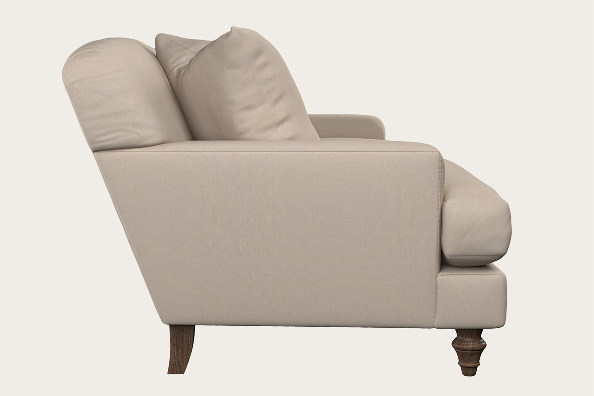 Side view of the Nkuku Deni Large Corner Sofa in Brera Linen Smoke, showcasing two seat cushions, two back cushions, and exposed dark wooden legs; set against a solid off-white background that highlights British quality craftsmanship.