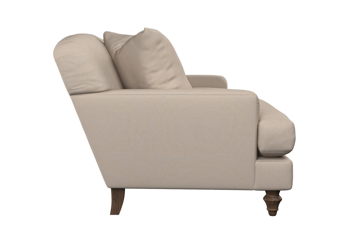 Side view of the Nkuku Deni Large Corner Sofa in Brera Linen Smoke, featuring plush seat and back cushions with linen upholstery. The sofa displays elegant wooden turned front legs with straight back legs, highlighting its superior British craftsmanship. Shown against a plain white background, the piece exudes comfort and refined style.