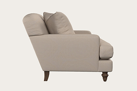 Side view of the Deni Love Seat - Recycled Cotton Natural by Nkuku, featuring beige recycled cotton upholstery, two back cushions, plush seat, rolled armrest, and dark wooden legs on a plain light background—a refined example of British sofa craftsmanship and handcrafted hardwood furniture.