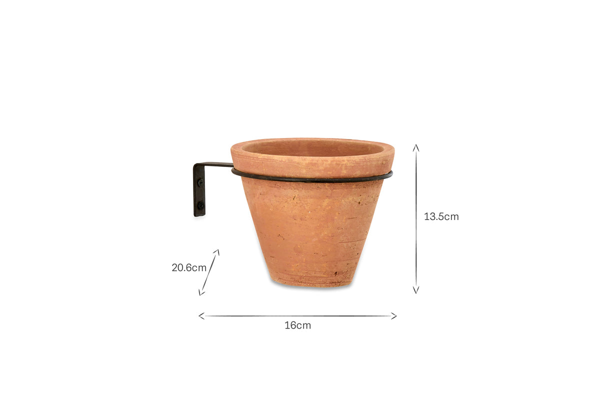 The Jara Single Wall Hung Planter by nkuku is shown with a terracotta pot and metal wall-mount bracket, ideal for wall displays. The pot is 16cm wide, 13.5cm tall, and the bracket extends 20.6cm from the wall. Background is white with marked dimensions.