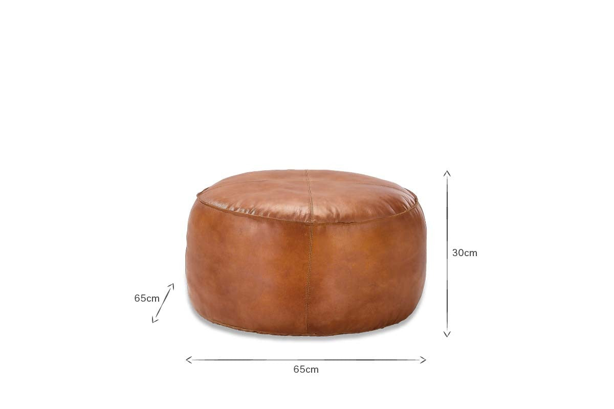 The nkuku Nadu Leather Pouf in Aged Tan features visible stitching and a round design. Measuring 65 cm wide/deep and 30 cm tall, it’s perfect as a stylish footrest or extra seat for any room, shown here on a white background.
