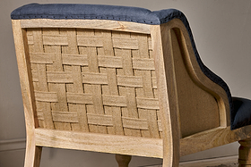 A close-up of the Elbu Deconstructed Linen Armchair by nkuku highlights its light mango wood, exposed woven burlap back, and charcoal linen fabric along the edges and seat—showcasing rustic charm with a modern twist.