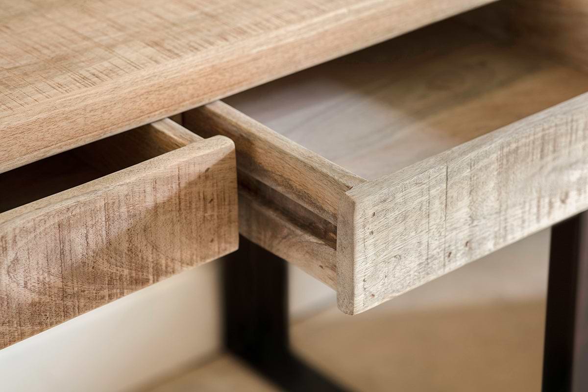Close-up of the nkuku Fia Mango Wood Desk - Natural, featuring two rectangular drawers (one partially open), showcasing light mango wood grain on slim dark metal legs against a softly blurred background.