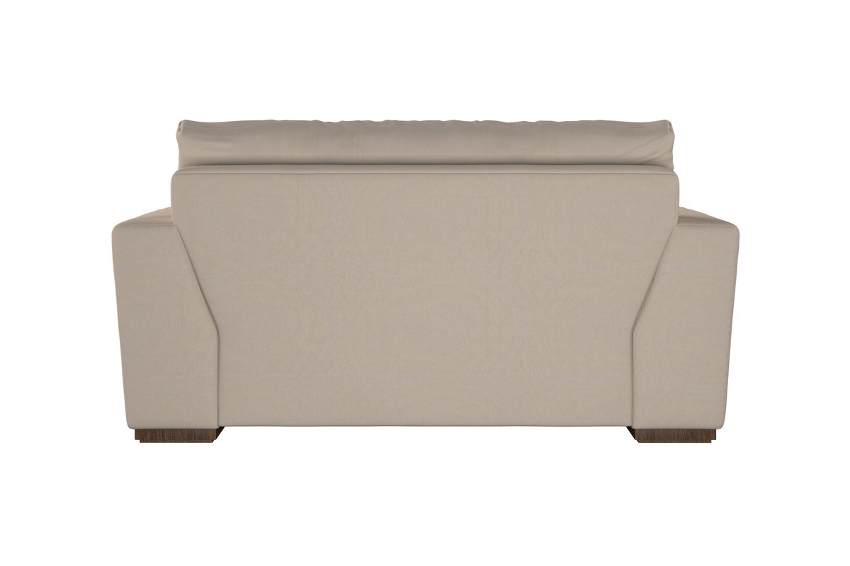 The Guddu Large Right Hand Chaise Sofa by Nkuku is expertly crafted, showcasing British craftsmanship. Viewed from the back, it features a flat backrest, wide armrests, and short wooden legs at each corner. Upholstered in heavyweight washed Brera Linen Indigo, this elegant sofa stands out against a plain white background.