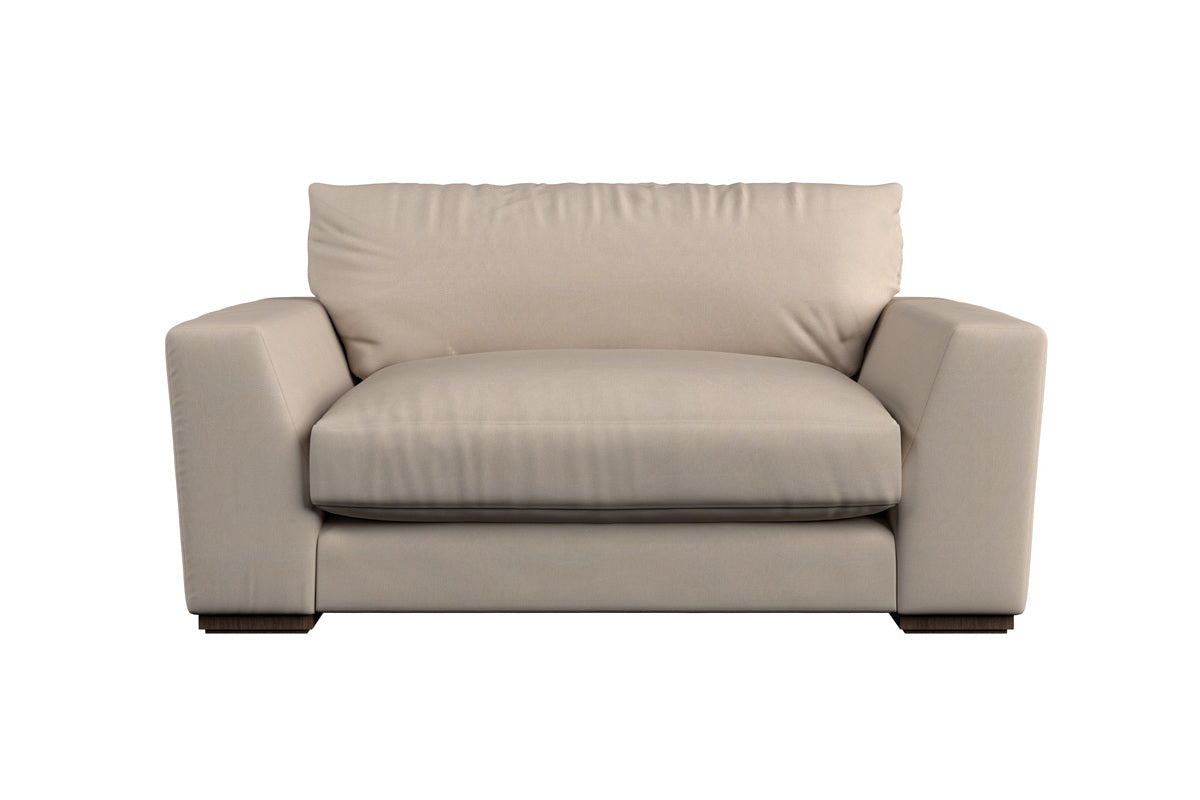 A contemporary beige loveseat with plush cushions and wide armrests sits low on dark wooden feet, featuring a soft, heavyweight washed linen upholstery and a minimalist design that reflects British craftsmanship. Perfect for modern living rooms, it pairs beautifully with the Nkuku Guddu Large Right Hand Chaise Sofa in Brera Linen Indigo to create an elevated yet comfortable space.