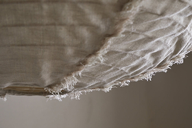 Close-up of the Hirana Cotton Lampshade by nkuku in natural, large size: off-white textured cotton with frayed edges and visible stitching, softly draped—perfect for adding warmth to any bedroom or living space.