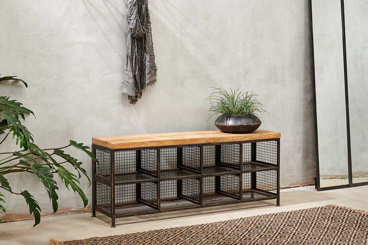 The nkuku Hasa Industrial Storage Bench features a mango wood top and black metal wire mesh cubbies, perfect for hallway storage. Styled with a dark bowl planter, it suits grey walls, jute rugs, large plants, and mirrors.