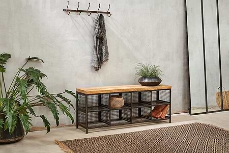 The nkuku Hasa Industrial Storage Bench features a mango wood top and wire mesh shelves for hallway storage. Perfect for plants on top, plus baskets or boots below, it combines urban style and function in your entryway.