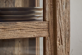 Close-up of the Ibo Reclaimed Wood & Glass Cabinet - Natural - Tall by nkuku. Round wooden plates are stacked inside, showcasing the cabinet’s rustic charm and natural wood grain.
