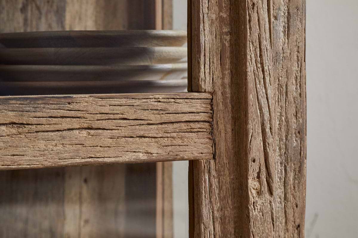 Close-up of the Ibo Reclaimed Wood & Glass Cabinet - Natural - Tall by nkuku. Round wooden plates are stacked inside, showcasing the cabinet’s rustic charm and natural wood grain.