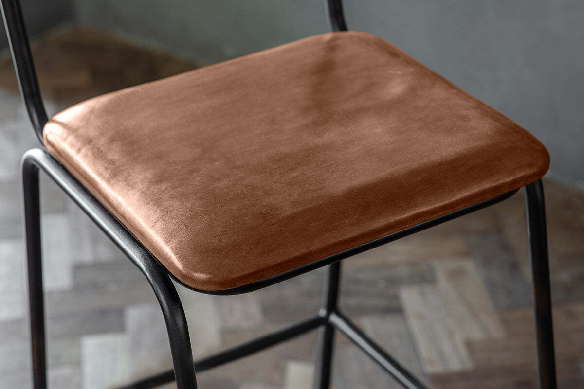 A close-up of nkuku’s Iswa Leather & Cane Counter Chair in aged tan, showing its square seat in rich leather with subtle color variations, set on a sleek black metal frame—perfect for adding style to any kitchen island.