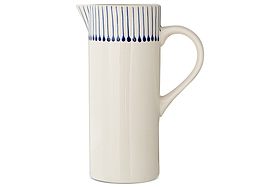 The Iba Jug - Indigo by nkuku is a tall, white ceramic pitcher featuring artisanal craftsmanship, a curved handle, narrow spout, and thin indigo lines near the rim for a modern touch.
