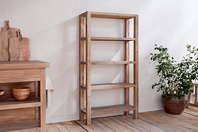 The Ibo Reclaimed Wood Shelf – Natural – Wide by nkuku, with five shelves, stands on a wooden floor beside a potted plant, adding rustic charm to your space.