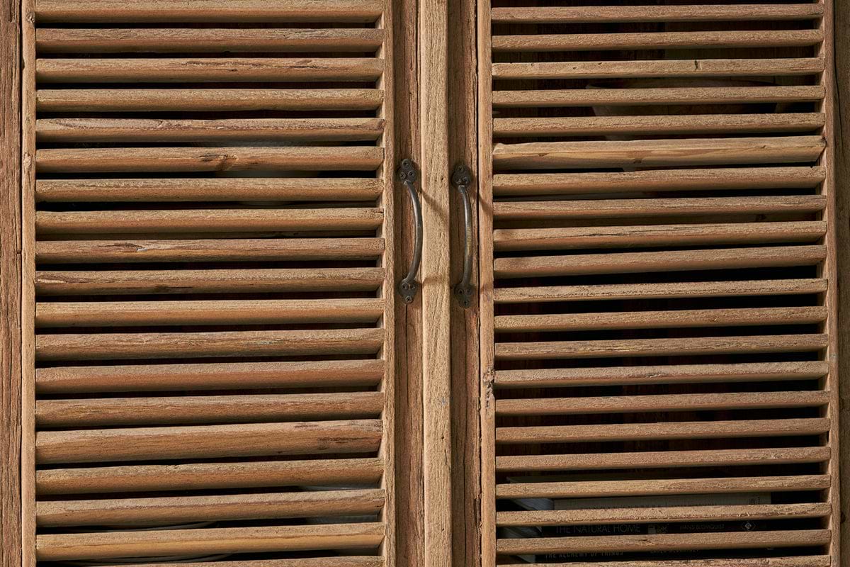 The nkuku Ibo Reclaimed Wooden Slatted Cabinet – Natural (Large) features rustic metal handles and highlights Indian artisan craftsmanship.