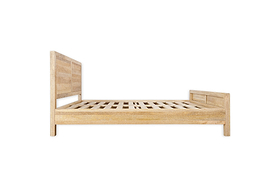 The nkuku Indali Mango Wood Bed - Natural is shown from the side, with a slatted base, tall headboard, and matching footboard—all crafted from mango wood in a natural light finish and set against a plain white background.