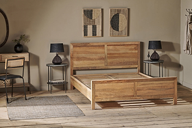 An Indali Mango Wood Bed - Natural by nkuku anchors a minimalist bedroom with light wood floors. Round nightstands with black lamps flank the bed, abstract art hangs above the headboard, and beige walls add a cozy, modern touch.