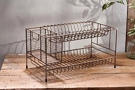 The nkuku Inkollu Dish Rack features two tiers of open wire metal shelves and slim legs for a rustic, industrial look. Perfect for drying plates and utensils, it sits stylishly on your countertop, casting airy shadows as sunlight streams in.
