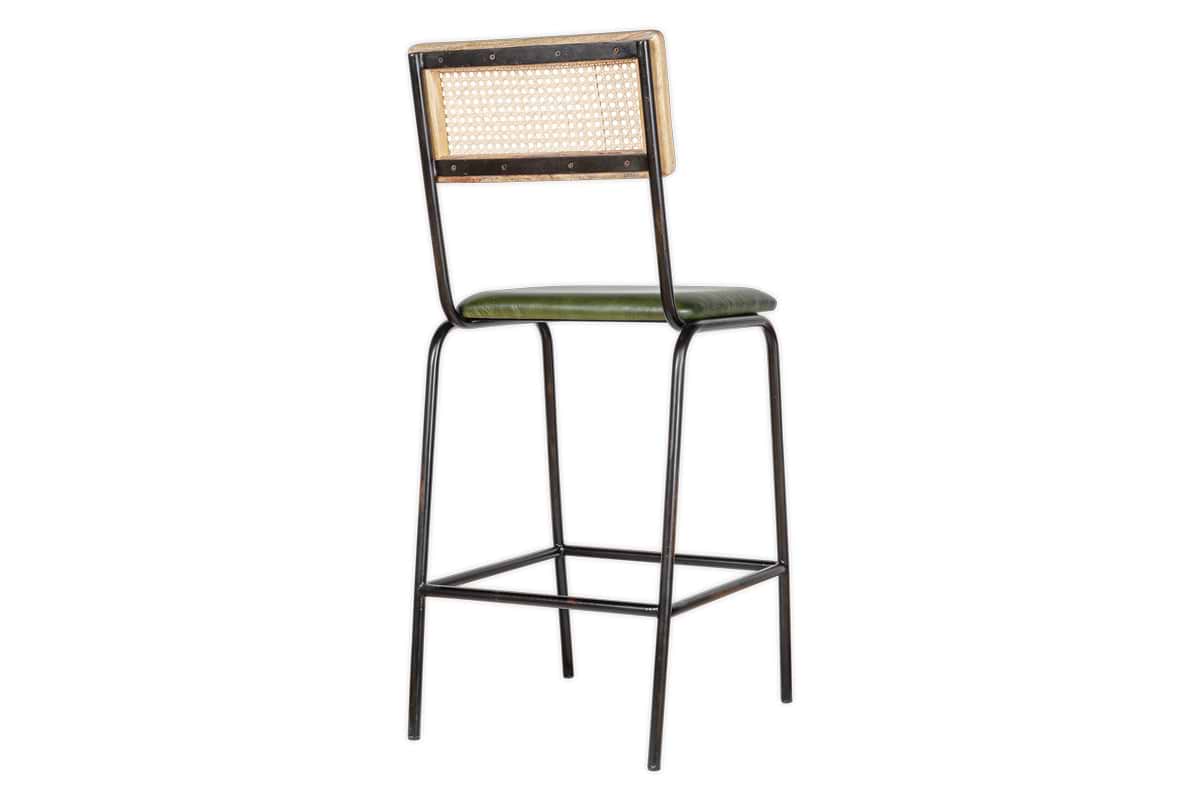 The Iswa Leather & Cane Counter Chair by nkuku features a black metal frame, square woven cane back, and rich green leather seat. Slender legs with a footrest blend minimalist, industrial, and vintage styles for your kitchen island.