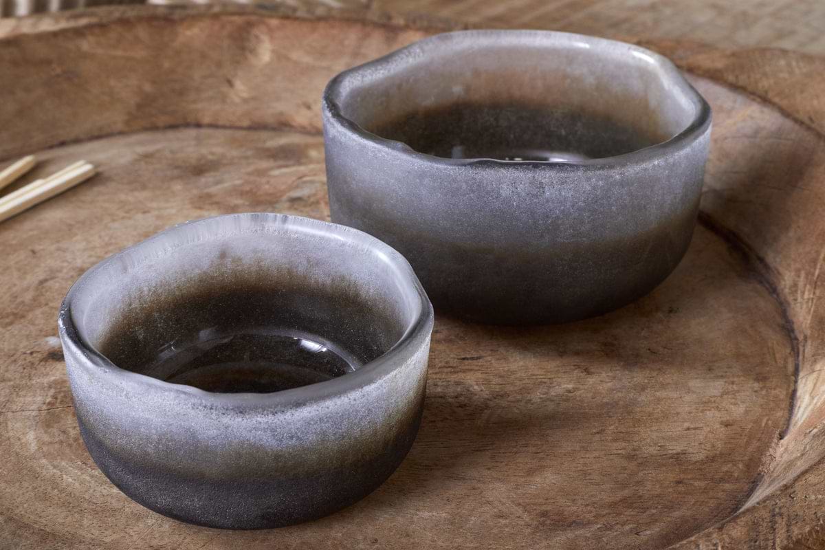 The Janka Tealight Holders by nkuku (set of 2) feature a handmade smoky charcoal finish and uneven rims, blending dark tones with rustic charm—perfect accents for cozy home decor.