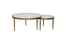 The nkuku Jiya Iron & Glass Nested Coffee Tables in brass feature glass tops and bronze metal frames with an antique brass finish, shown against a white background.