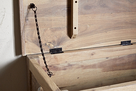 The Karadi Reclaimed Wood Storage Bench - Natural by nkuku features an open, unfinished wooden chest with a hinged lid supported by a black metal chain, making it an ideal rustic storage bench for any space.