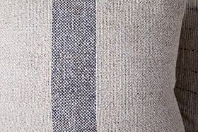 A close-up of the nkuku Kallu Wool & Cotton Cushion Cover - Natural, featuring a visible coarse weave and a vertical dark gray stripe running down the center.