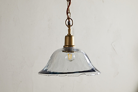 The Keju Organic Shape Recycled Glass Pendant in clear by nkuku features a stylish glass shade suspended from a chain, bringing elegant flair to any room.
