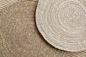 The nkuku Keso Woven Placemats - Brown (Set of 4) feature overlapping concentric circles in natural fiber shades, adding minimalist charm to your table and enhancing any light wooden surface.