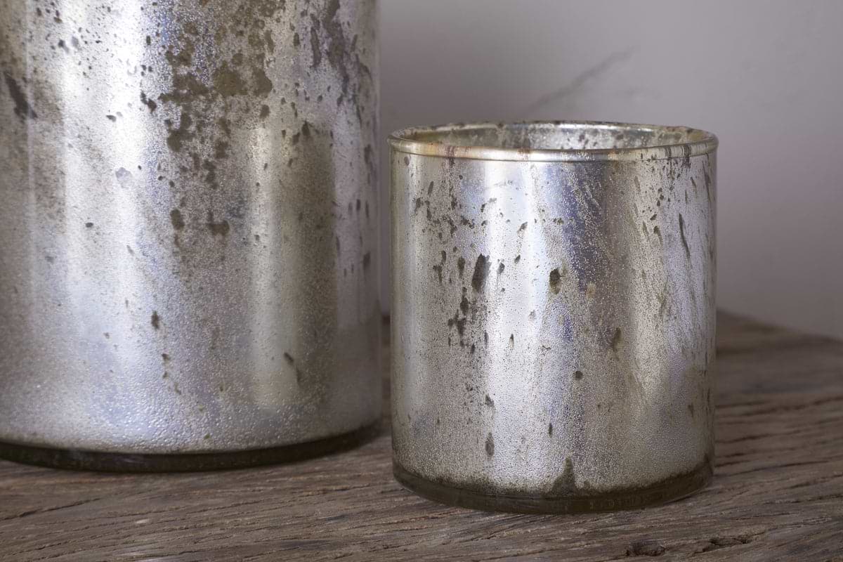 Two rustic gold Kunjari Tealight Holders by nkuku, one large and one small, rest on a wooden surface; the smaller holder sits fully in front—ideal accents for tealights and adding rustic charm.