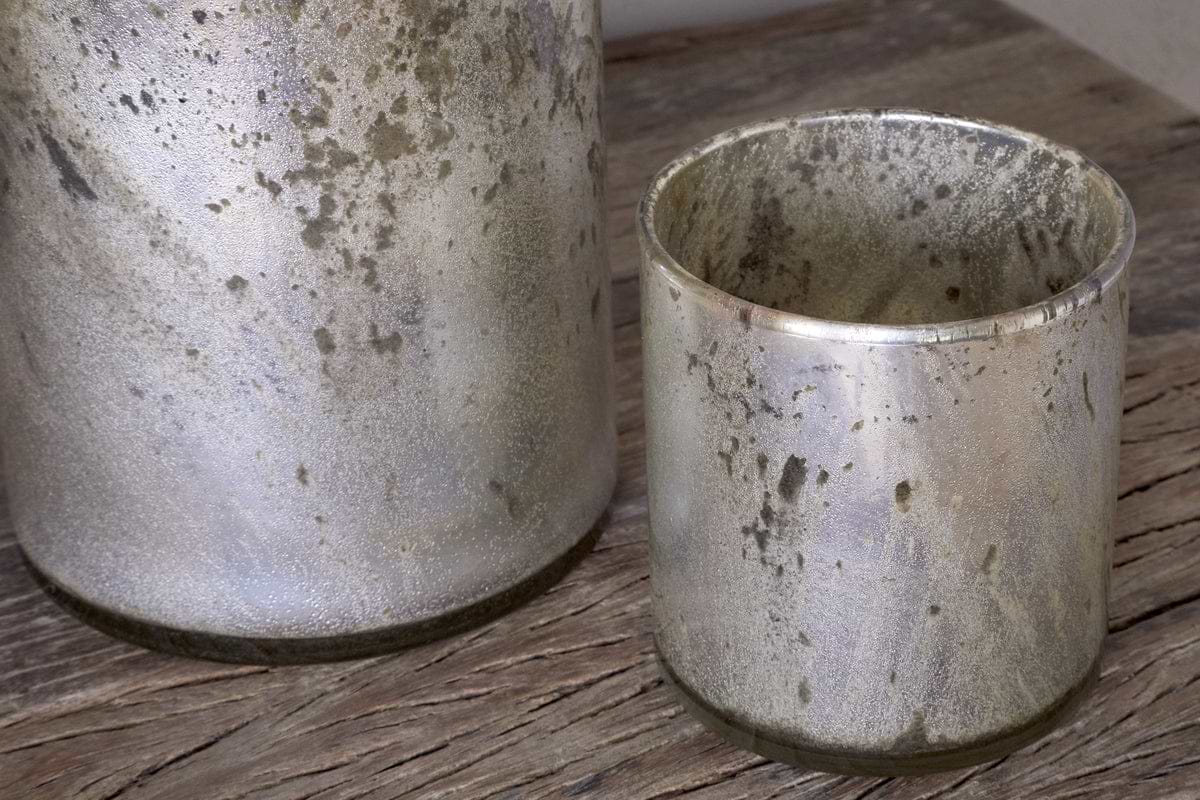 Two Kunjari Tealight Holders by nkuku in rustic gold with a weathered, speckled finish sit on a wooden surface—ideal for adding charm and classic rustic style to your space.