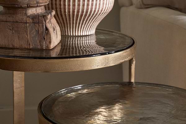 A close-up of nkukus Khidki Cast Metal & Glass Nesting Side Tables (Set of 2), showcasing hammered aluminium details and antique brass accents.