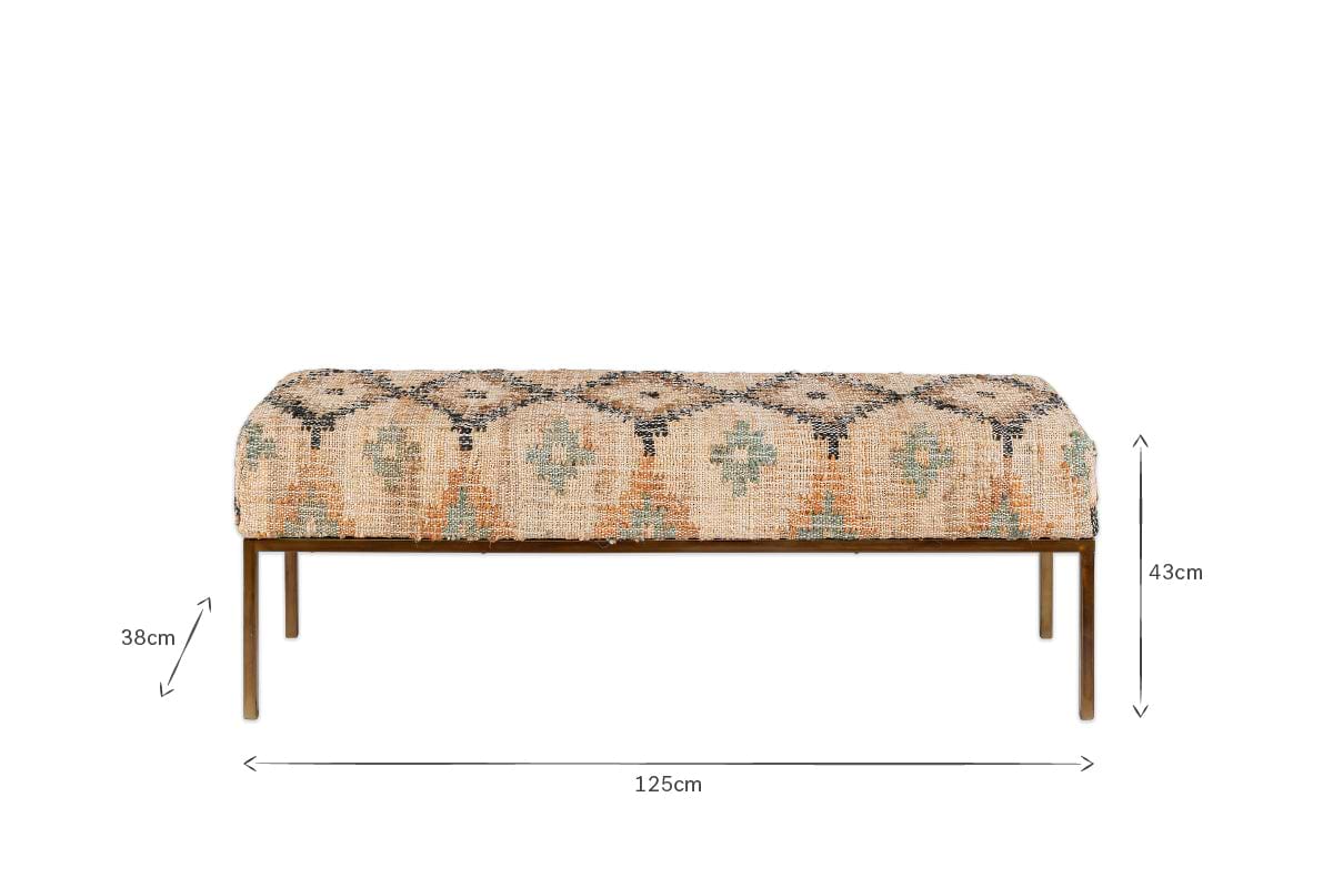 The Kesu Kilim & Iron Bench by nkuku features patterned beige and blue fabric, four slender iron legs, and measures 125cm wide, 38cm deep, and 43cm high. The front-facing image highlights its dimensions with measurement arrows.
