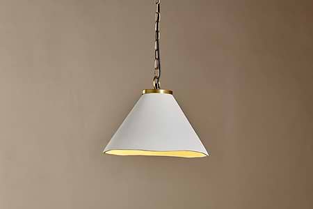 The Kiara Organic Shape Ceramic Pendant Light by nkuku features an off-white, wide cone shade and antique brass details. Hanging from a metal chain, it casts a soft downward glow—ideal for minimalist, modern kitchen lighting.