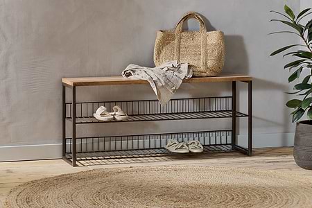 The nkuku Kiyoma Iron & Wood Low Standing Shelves in Natural display a straw tote, folded linen, and sandals. A round jute rug on the wooden floor brings warmth to the industrial space.
