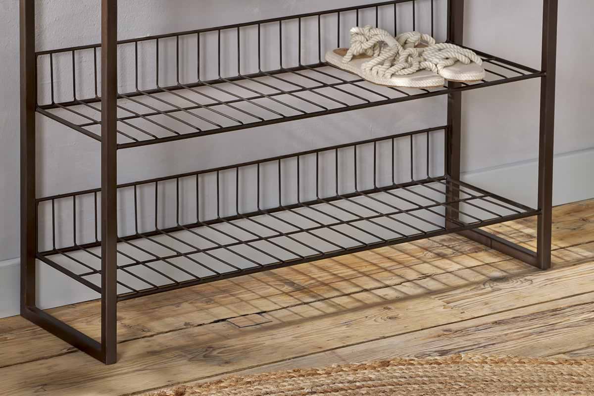 The nkuku Kiyoma Iron & Wood Tall Standing Shelves - Natural features three metal and wood shelves against a light wall. Braided rope slippers sit neatly on the top shelf, while the bottom shelf remains empty, lending an industrial touch to the space.