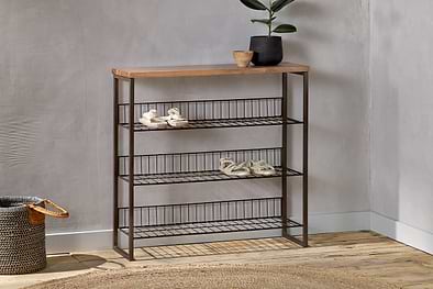 The nkuku Kiyoma Iron & Wood Tall Standing Shelves - Natural features three wire shelves and a mango wood top, perfect against a gray wall. A black plant pot, wooden bowl, woven basket, and round rug complete this organized entryway.