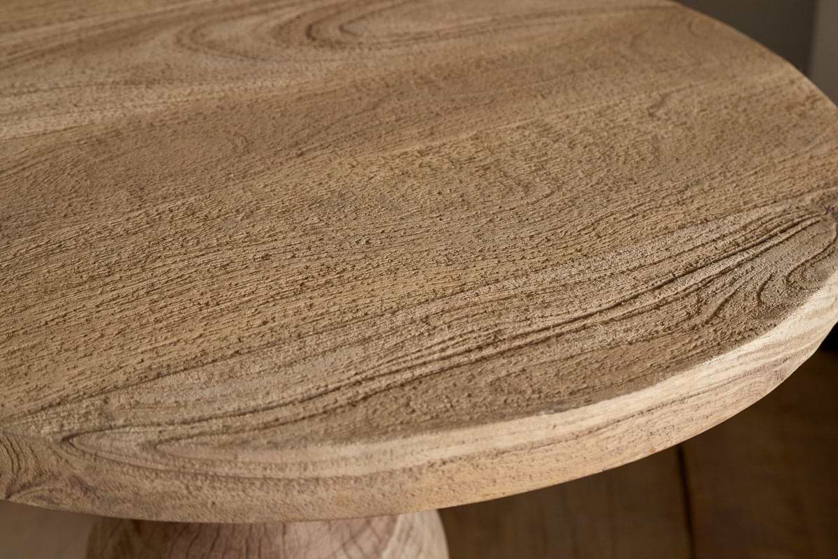 Close-up of the nkuku Laya Round Carved Side Table in Natural, featuring a smooth raw wood finish that highlights the natural grain and texture, with a gently rounded tabletop edge.