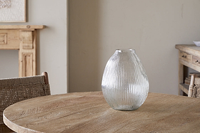 The Linsy Ribbed Glass Vase by nkuku, with its clear textured finish, adds a stylish touch to the table setting.