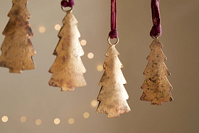 The nkuku Mishti Tree Baubles - Antique Brass (Set of 4, Small) feature a rustic gold finish and hang from maroon ribbons, creating a warm festive atmosphere with their antique charm.