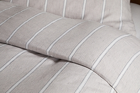 Close-up of a neatly made bed dressed in the Mora Hemp & Cotton Duvet Cover in Stone Grey by nkuku, showcasing soft, textured fabric for breathable comfort.