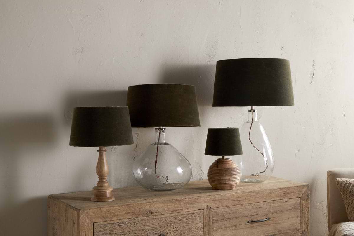 Four nkuku Mendai Velvet & Linen Lampshade lamps in moss green, with clear glass, ribbed round wood, and turned wood bases, are arranged on a wooden cabinet—creating stylish decorative lighting for any room.