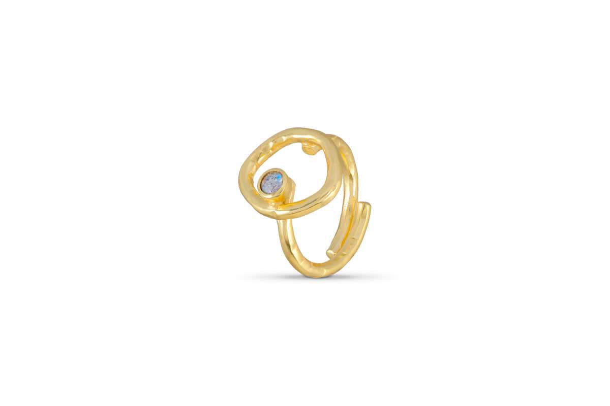 The Mari Labradorite Ring - Gold by nkuku is a hypoallergenic, gold-plated open band with an abstract, looped design and a round blue labradorite gemstone, displayed against a plain white background.