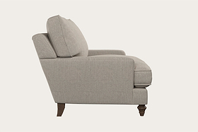 A side view of the Marri Love Seat - Brera Linen Natural by Nkuku, featuring light gray linen upholstery, a thick back cushion, a plush seat cushion, and dark wooden legs handcrafted from a sturdy hardwood frame, shown against a plain white background.