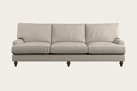 The Nkuku Marri Super Grand Sofa in Brera Linen Natural features a generous three-seat design with plush back and seat cushions, gently angled armrests, and elegant dark wooden turned legs, set against a plain light background. Its handcrafted linen upholstery boasts a soft, textured feel that enhances the sofa's classic and comfortable appearance—a testament to fine craftsmanship inspired by Nkuku’s Nottinghamshire workshop.