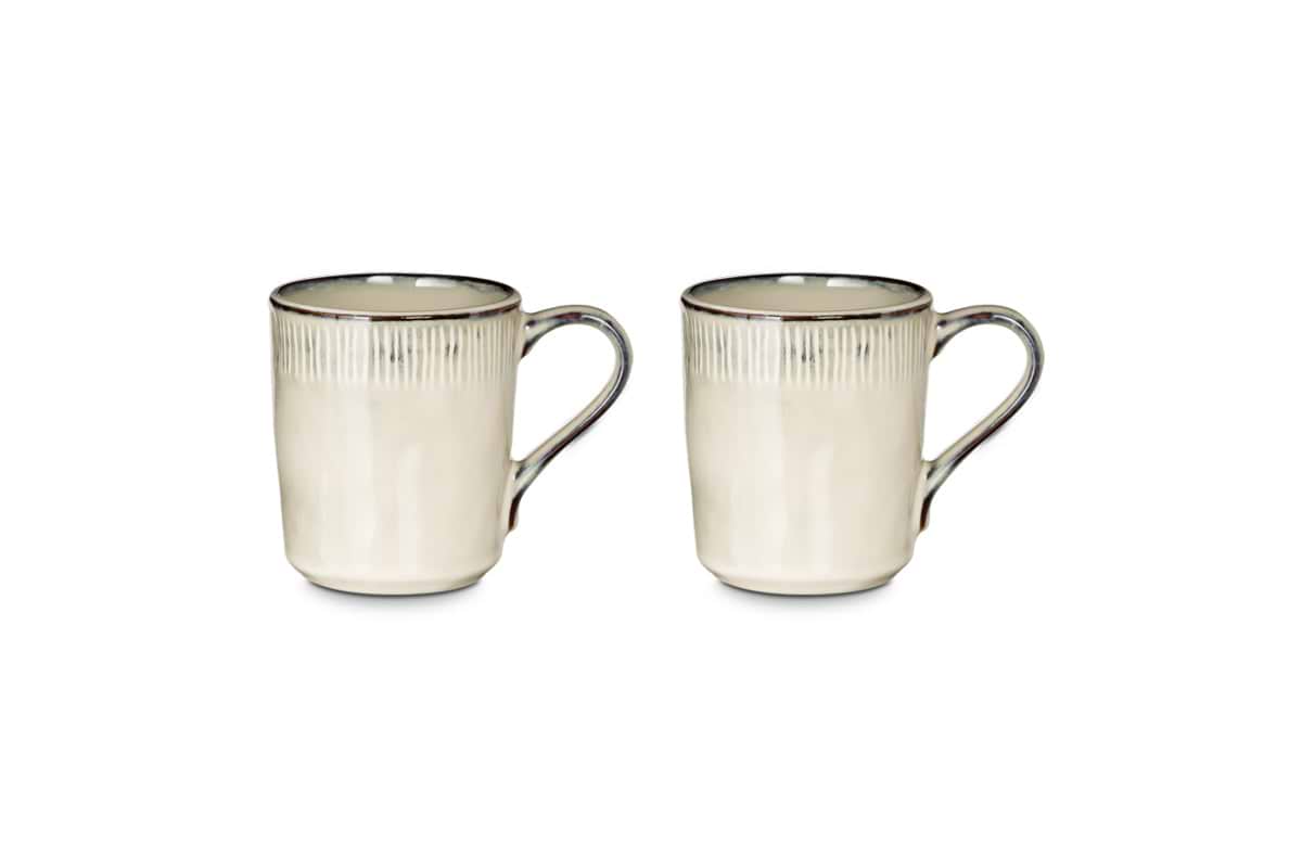 The nkuku Malia Mug - Cream (Set of 2) features a textured rim, dark brown accents, and a stunning reactive glaze, shown side-by-side on a white background.