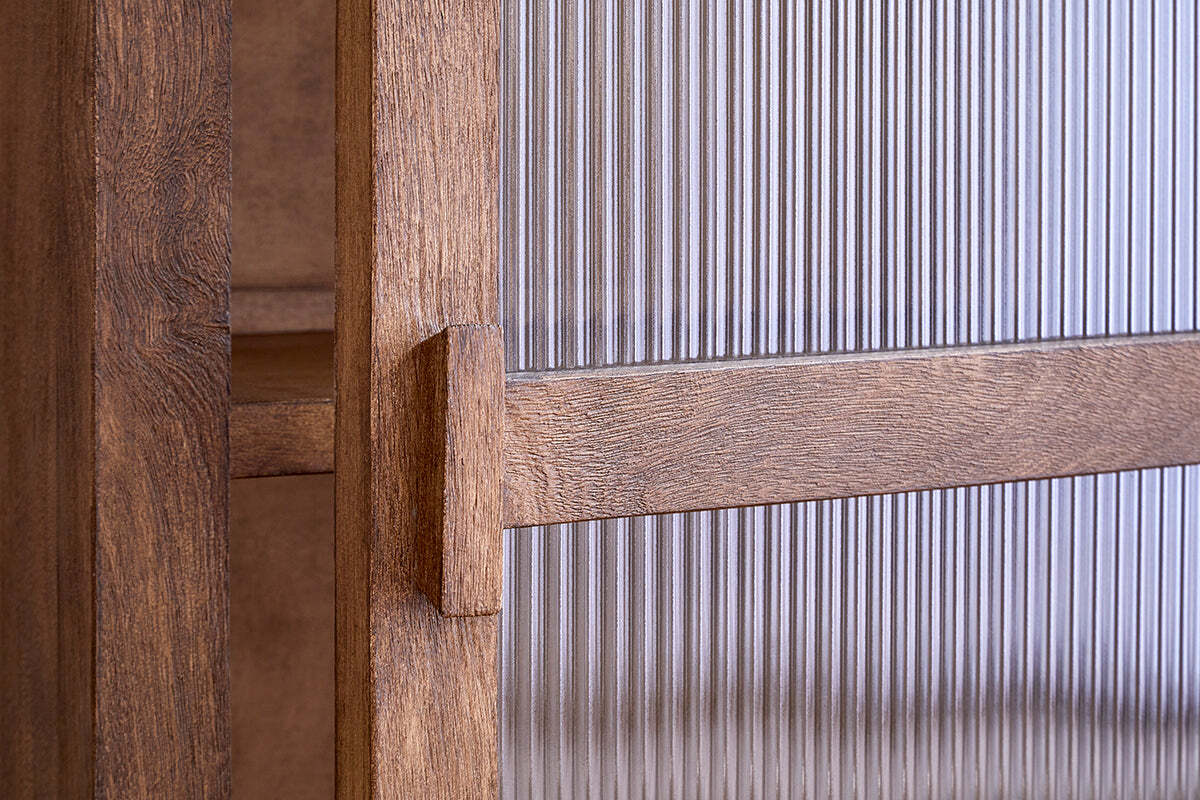 Close-up of the Mendani Mango Wood & Fluted Glass Low Cabinet by nkuku, featuring a walnut-stained finish, vertical handle, and fluted glass panel in a wooden frame that highlights the wood grain, joinery, and detailed craftsmanship.