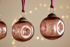 The Nishan Pinched Baubles - Copper (Set of 4) by nkuku are elegant recycled glass ornaments that add a charming, festive touch to your décor.
