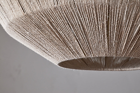 Close-up of the Nilaveli Woven Jute Sphere Pendant - Natural by nkuku, featuring a dome-shaped shade wrapped in tightly wound jute for a textured, linear pattern. The image highlights its bottom edge and surface against a soft, neutral background.