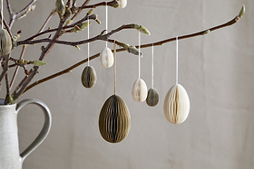 A ceramic jug with bare branches displays nkuku's Piani Hanging Paper Decoration in Cream (Set of 4), creating a minimal, natural spring decor scene against a plain light wall.