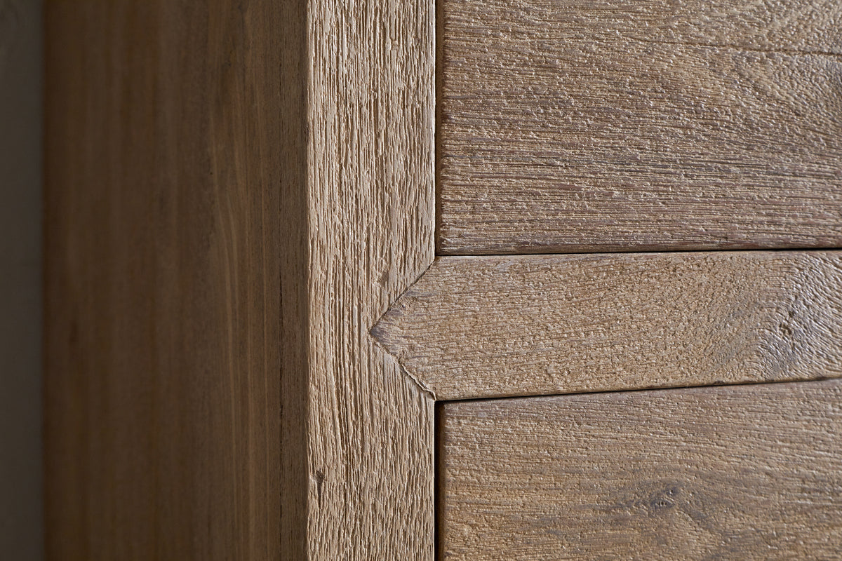 Close-up of the Iya Reclaimed Wood Tall Boy Chest of Drawers by nkuku shows precise joinery at the corner. The natural finish highlights textured grain as two panels meet with clean, mitered edges for a crisp, geometric look.